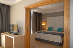 a hotel room with a bed and a television at Protur Sa Coma Playa Hotel & Spa in Sa Coma