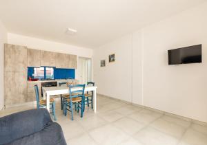 a living room with a table and chairs and a tv at Villetta Verdi a Pescoluse in Marina di Pescoluse