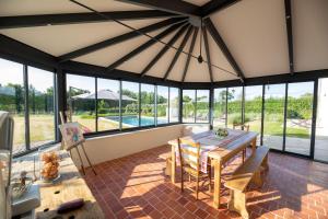 a dining room with a table and chairs and windows at Au Manoir des Loges in Quettreville-sur-Sienne