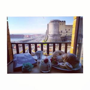 uma mesa com um prato de comida numa varanda com um castelo em Venere Bellevue by Babylon Stay em Nápoles