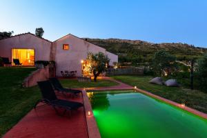 a backyard with a pool with two chairs and a house at Vale do Ninho Nature Houses in Ferraria de São João