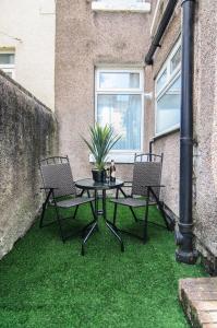 a patio with a table and two chairs on grass at RIVERPOOL - LUXRY SUITS FOR FOOTBALL FANS NEAR AnFIELD STADIUM in Liverpool