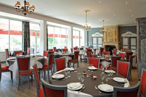 un comedor con mesas, sillas y ventanas en Hotel Royal Vézère, en Le Bugue