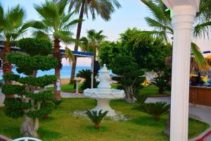 une grande fontaine blanche dans un parc planté de palmiers dans l'établissement Club Hotel Rama, à Beldibi
