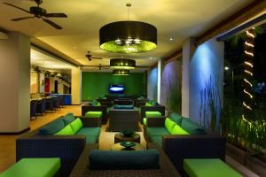 a lobby with green couches and a bar at Praja Hotel in Denpasar