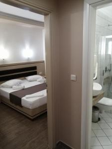 a bedroom with a bed and a bathroom with a sink at Hotel Katerina in Keramoti