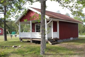 uma casa vermelha e branca com um alpendre em Solvändans Stugby em Byxelkrok