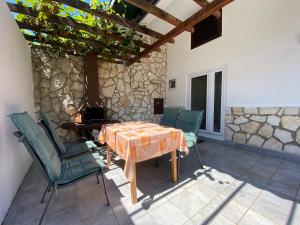 een patio met een tafel en stoelen en een stenen muur bij Apartment Mandica in Savudrija