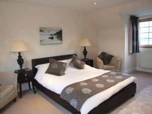 a bedroom with a large bed and a chair at Trien Lodge in Carbost