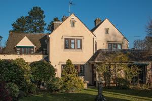 een groot wit huis met een tuin bij Coombe House in Bourton on the Water