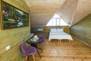 フジュルにあるVilla Malina Olkhon Baikalのログキャビン内のベッドルーム(ベッド1台、紫色の椅子付)
