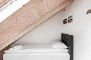 Bett in einem Zimmer mit Holzdecke in der Unterkunft Small attic rooms in Kaunas old town in Kaunas