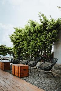 鵝鑾的住宿－墾丁船帆石 莎莎之拉夢海景民宿，坐在树荫庭院的一组椅子