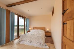 a bedroom with a bed and a large window at The Oaks - Ash Farm Cotswolds in Stow on the Wold