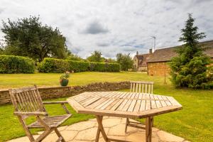 a wooden table and two chairs in a yard at The Oaks - Ash Farm Cotswolds in Stow on the Wold