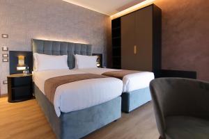 a bedroom with a large bed and a chair at Hotel Bell'arrivo by Dori in Peschiera del Garda