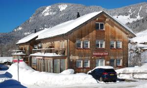 ein Holzhaus mit einem Auto im Schnee in der Unterkunft Ferienwohnungen Schantl in Schoppernau