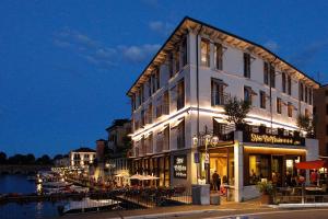a white building with lights in front of a river at Hotel Bell'arrivo by Dori in Peschiera del Garda