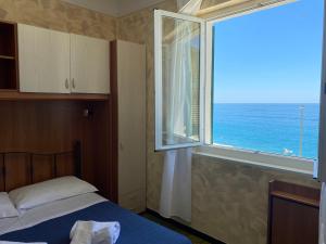 una camera da letto con finestra con vista sull'oceano di Caravella a Deiva Marina