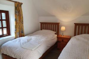 a bedroom with two beds and a lamp and a window at The Gardeners Cottage at Wells House in Glenranny