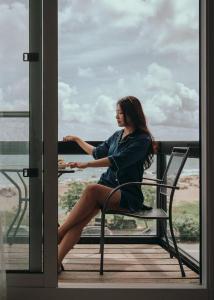 鵝鑾的住宿－墾丁船帆石 莎莎之拉夢海景民宿，坐在阳台上椅子上的女人