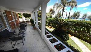 eine Veranda eines Hauses mit Stühlen und Palmen in der Unterkunft VILLA AZZURRA beachfront Mondello - Palermo in Palermo