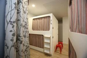 Habitación infantil con estante de libros y silla roja en dpaso Urban Hostel en Pontevedra