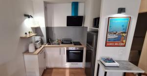 a small kitchen with white cabinets and a stove at Perle rare à 250m de la plage ! Climatisé avec Parking, balcon & WiFi in Sainte-Maxime
