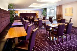 uma sala de jantar com mesas e cadeiras de madeira em Holiday Inn Express Cambridge, an IHG Hotel em Cambridge