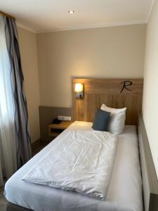 a bedroom with a white bed with a wooden headboard at Hotel Rosenbusch in Großheubach
