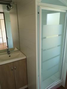 een glazen douche in een badkamer met een wastafel bij Camping Le Ragis in Challans