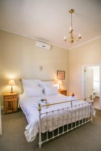 una camera da letto con un grande letto con lenzuola e cuscini bianchi di 54 on Middle - Solar-powered stay a Graaff-Reinet