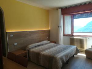 a bedroom with a bed and a large window at Albergo Ristorante Sargas in Cevo