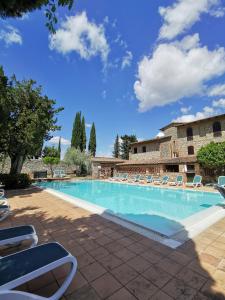 une piscine avec des chaises longues et un bâtiment dans l'établissement Hotel Pescille, à San Gimignano