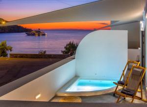 eine Badewanne auf einem Balkon mit Blick auf das Wasser in der Unterkunft Oro Suites in Kini