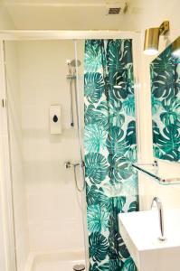a bathroom with a shower with green leaves wallpaper at Family Hotel Kooyk in Amsterdam +47 photos