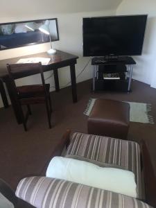 ein Wohnzimmer mit einem Sofa, einem Tisch und einem TV in der Unterkunft Mackenzies Accommodation in East London