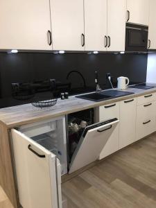 una cocina con armarios blancos y fregadero en Apartament Kora en Kołobrzeg