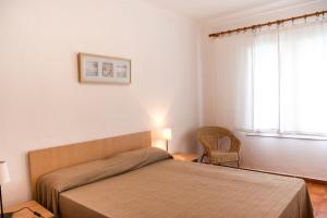 Un dormitorio con una cama y una silla y una ventana. en Casas Montgrí, en Empuriabrava