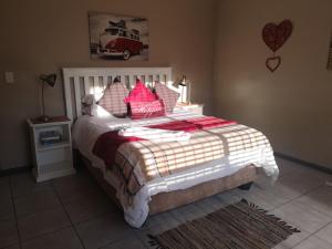 um quarto com uma cama grande e almofadas vermelhas em Mackenzies Accommodation em East London