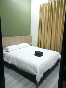 a bedroom with a bed with white sheets and a window at Serantau Mayang by the Bliss in Bagan Serai