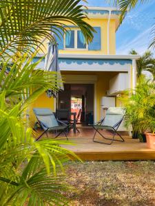 une maison avec deux chaises sur une terrasse en bois dans l'établissement Maison mitoyenne , piscine,Citerne, jardin, parking, plage, au Gosier