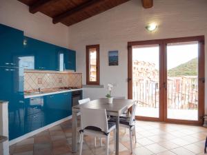 uma cozinha com armários azuis e uma mesa e cadeiras em Il Blu Tanca Piras em Nebida