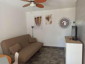 a living room with a couch and a ceiling fan at Appartement à Marseillan plage accès direct à la plage in Marseillan +2 photos