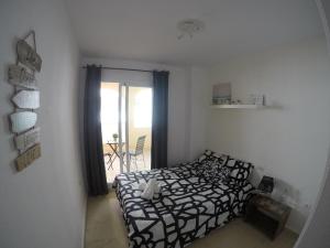 a bedroom with a bed with a black and white comforter at Bonita y moderna habitación a 300m de la playa in Benalmádena