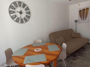 sala de estar con mesa y reloj en la pared en Appartement à Marseillan plage accès direct à la plage, en Marseillan