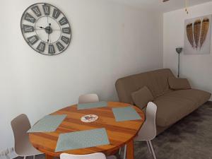 a living room with a table and a clock on the wall at Appartement à Marseillan plage accès direct à la plage in Marseillan