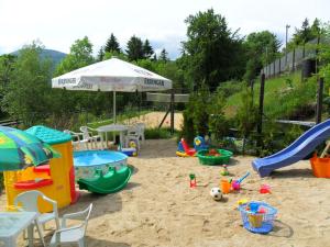 un parque infantil con juguetes en la arena y una sombrilla en Willa Biała Dolina, en Szklarska Poręba