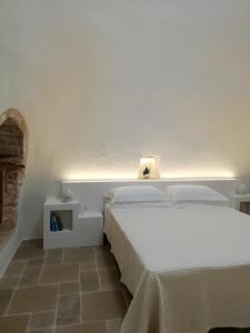 a bedroom with a white bed with a light above it at Pietra Pesara in Locorotondo