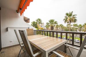 a wooden table and chairs on a balcony with palm trees at Parque Santiago 1 Duplex 2A014 in Playa de las Americas